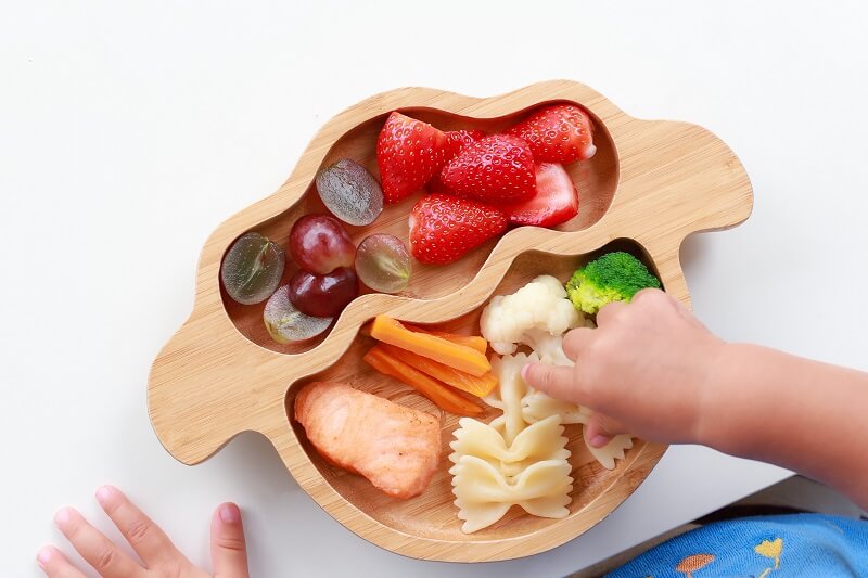 Child reaching for food on a kids plate